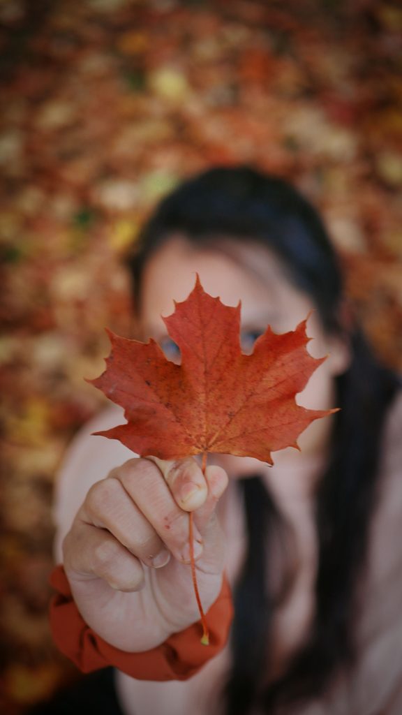 woman holding a fall leaf